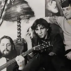 Trzech muzyków zespołu Universe pozuje z gitarami w przytulnym wnętrzu.