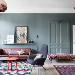 Gemütliche, bunte Wohnung mit Ledersofa, gemusterten Teppichen und auffälligen Lampen.