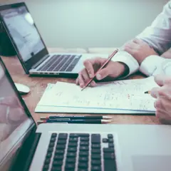 Deux personnes travaillent sur un projet, l'une rédigeant une lettre de motivation pour licence pro sur un ordinateur portable.