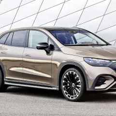 Brązowy Mercedes EQC na ładowaniu przy nowoczesnej ścianie. Stylowy SUV z elektrycznym napędem gotowy do drogi.