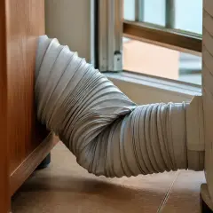El tubo de un aire acondicionado portátil, conectado a una ventana, parece un poco torcido. ¡Espero que mi pinguino no enfria!