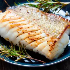 Zdrowa ryba zębacz, soczysty filet z chrupiącą skórką, podany z rozmarynem na talerzu.