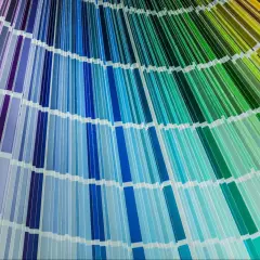 Próbnik kolorów rozłożony wachlarzowo, od fioletów i błękitów po zielenie i żółcie. Paleta barw przypomina przejścia między modelami CMYK i RGB.