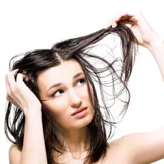 Mujer con cabello mojado, pensativa sobre lavarse el pelo todos los días.