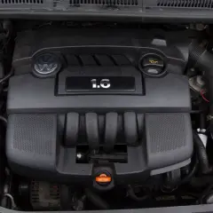 Silnik Volkswagena z oznaczeniem 1.6 MPI. Widoczny jest czarny plastikowy kolektor, logo VW i zbiornik płynu chłodniczego.