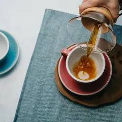 Kawa przelewana do filiżanki, idealna na drzemkę kofeinową. Obok pusta, błękitna filiżanka.