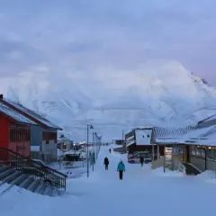 Śnieżna ulica w Longyearbyen, najwyżej położonym mieście na świecie, z górami w tle.