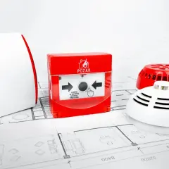Technische Brandschutzgeräte wie Melder und Alarmgeber auf Bauplänen.