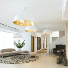 Elegante recibidor con lámparas de filamento doradas, sofá curvo, alfombra redonda y detalles rústicos en piedra.