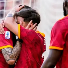 Dwóch piłkarzy z Rzymu świętuje bramkę, przytulając się. Na koszulkach widnieje logo Serie A.