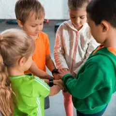 Dzieci w wieku 6-7 lat, tworząc krąg, łączą ręce. Może to być początek wspólnej zabawy lub rozwiązywania zagadek.