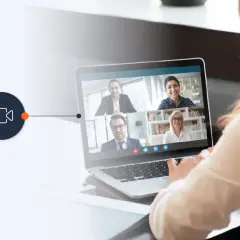 A woman uses a laptop for a video conference, connecting with colleagues via a WebRTC phone call.