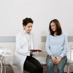 Medico spiega a paziente i risultati di un esame, forse un ecografia, discutendo del cerchiaggio cervicale.