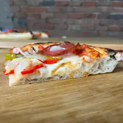 Ein Stück Pizza mit original italienischem Pizzateig Rezept Blech, belegt mit Salami, Paprika und Zwiebeln.