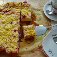 Pyszne ciasto drożdżowe z budyniem i owocami, posypane kruszonką. Gotowe do podania na talerzykach z widelcami.