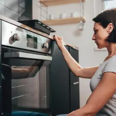 Donna controlla il display del suo forno a gas o elettrico prima di iniziare a cucinare.