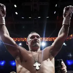 Boxer Oleksandr Usyk raises his arms in victory, his gloves high. He's a seasoned pro, not one of those top heavy amateurs.