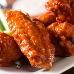 Un plato de alitas de pollo bañadas en salsa picante, acompañadas de bastones de apio fresco. ¡Un clásico irresistible!
