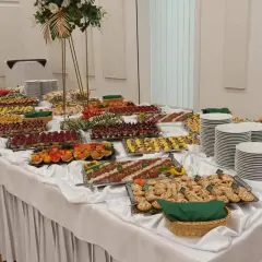 Stół z bogatym cateringiem: przekąski, sałatki, przystawki, talerze i dekoracje.