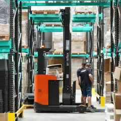 Wózek widłowy w magazynie, pracownicy przygotowują towar do wysyłki. Efektywny outbound logistics.