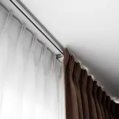 Elegancki karnisz mocowany do sufitu, z białymi i brązowymi zasłonami, tworzy przytulną atmosferę.