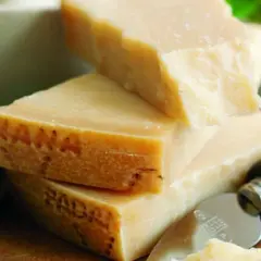 Pezzi di Grana Padano, formaggio a pasta dura, con un coltello da formaggio. La sua origine è legata alla Pianura Padana.
