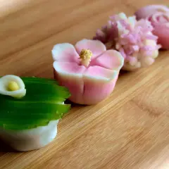 Délicates pâtisseries japonaises en forme de fleurs et de calla, aux couleurs pastel, sur fond de bois.