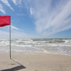 Czerwona flaga na plaży Bałtyku ostrzega przed niebezpiecznymi warunkami. Zamknięte plaże Bałtyk z powodu sztormu.
