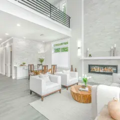 A modern living room with a fireplace, dining area, and kitchen, showcasing a full service interior design.