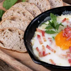 Un délicieux oeuf cocotte, parsemé de lardons croustillants, servi avec des tranches de pain de campagne.