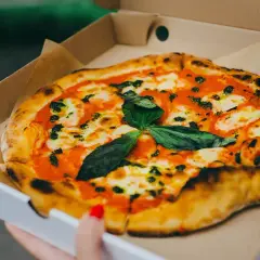 Pyszna pizza w kartonie na pizze, z sosem pomidorowym, mozzarellą i świeżą bazylią. Idealna na wynos!