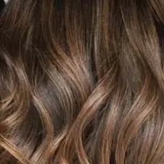 Glänzendes, glattes Haar mit Balayage in Braun-Caramel-Tönen, das wie flüssiges Gold fällt.