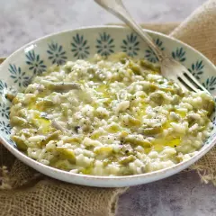 Un cremoso risotto con fagiolini, condito con olio d'oliva e pepe nero, servito in una ciotola decorata.