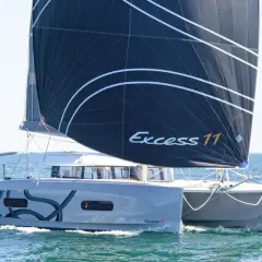 Catamarano Excess 11 con vela nera che naviga in mare aperto.