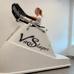 Kobieta ćwiczy na urządzeniu Vacu Shaper, które pomaga w modelowaniu sylwetki.