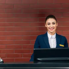 Uśmiechnięta recepcjonistka w hotelu, gotowa pomóc gościom. Jej angielski jest płynny, a uśmiech serdeczny.