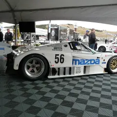 Legenda: Biały samochód wyścigowy Mazda 787B z numerem 56, gotowy do startu.