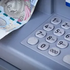 Dłoń wkłada banknot 500 zł do bankomatu. Zastanawiasz się, mbank ile idzie przelew?