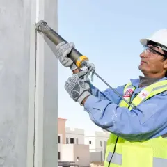 Obrero aplica Sikaflex para sellar juntas en construcción. Este adhesivo es ideal para unir y sellar materiales, asegurando durabilidad y resistencia.