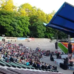 Tłum widzów na koncercie w amfiteatrze w Kołobrzegu. Scena z zespołem muzycznym i niebieski dach nad widownią.