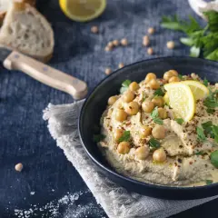 Cremiger Hummus, garniert mit Kichererbsen, Zitrone und Petersilie. Ein köstliches Hummus Rezept Original, bereit zum Dippen mit Brot.