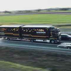 Ciężarówka Marathon International Logistics na autostradzie, obok samochód osobowy i laweta. To transport bilateralny przykład.