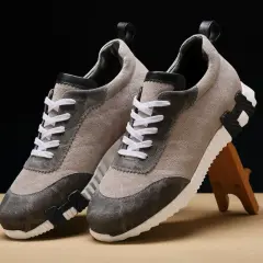 Ein Paar beigefarbene Sneaker mit grauen Akzenten und weißen Schnürsenkeln. Sie zeigen, wie orthopädische Schuhe aussehen können: stilvoll und bequem.
