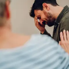 Mężczyzna z bólem głowy, cierpiący z powodu uzależnienia od kokainy, otrzymuje wsparcie od bliskiej osoby.