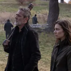 Maggie et Negan, le regard lointain, se tiennent côte à côte dans un paysage automnal. D'autres survivants travaillent en arrière-plan.