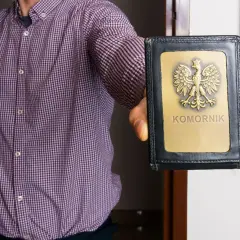 Mężczyzna w koszuli prezentuje legitymację komorniczą. To znak, że może nastąpić zajęcie egzekucyjne.