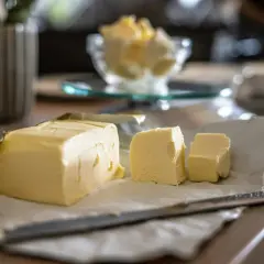 Un bloc de beurre, coupé en morceaux, sur du papier. Le beurre est-il un produit laitier ? Oui, il est fait de crème.