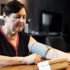 Kobieta w średnim wieku mierzy ciśnienie. Dba o prawidłowe ciśnienie tętnicze u 50-latka, monitorując je w domu.