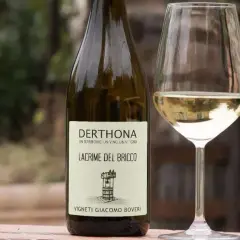 Calice e bottiglia di Derthona, vino Timorasso. Le caratteristiche di questo vino bianco piemontese sono freschezza e note minerali.