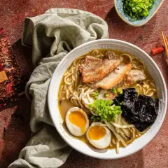 Jak zrobić ramen? Aromatyczny bulion, makaron, jajko na pół, chrupiąca wieprzowina i nori. Obok paczka goździków Prymat.